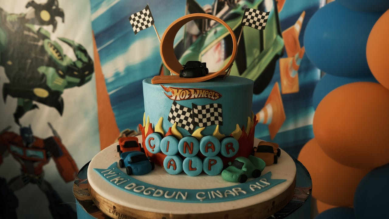 Vibrant Hot Wheels birthday cake with toy cars and a loop track, perfect for a childs party.