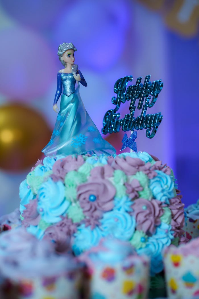 A Frozen-themed birthday cake with an intricate doll topper in vibrant colors, perfect for a childs celebration.