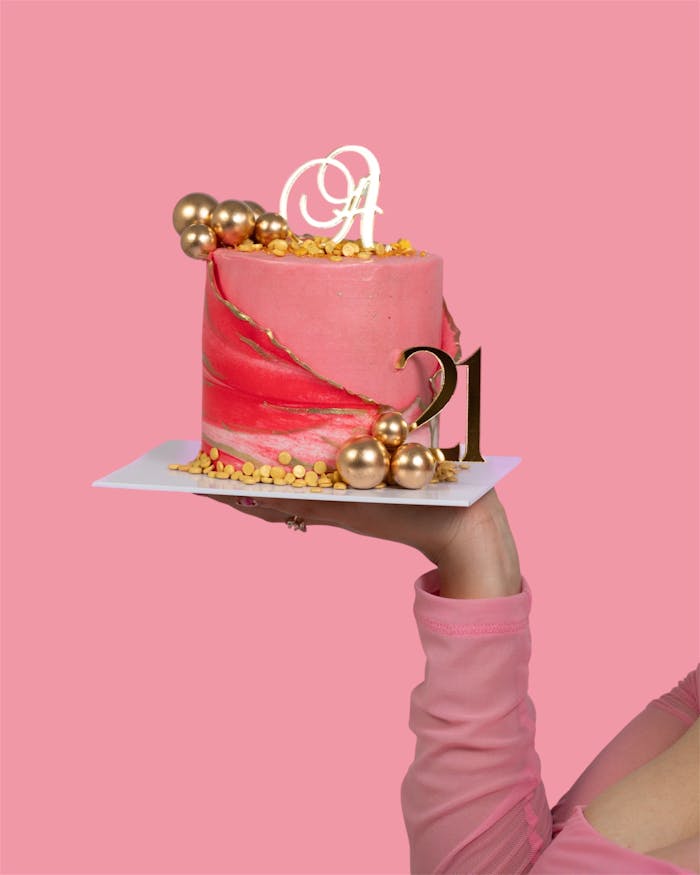 Stylish pink and gold birthday cake with a 21 number topper, ideal for celebrations.