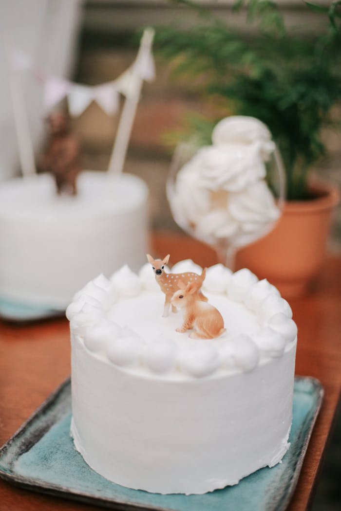 Elegant white cake decorated with deer figurines, perfect for celebrations.