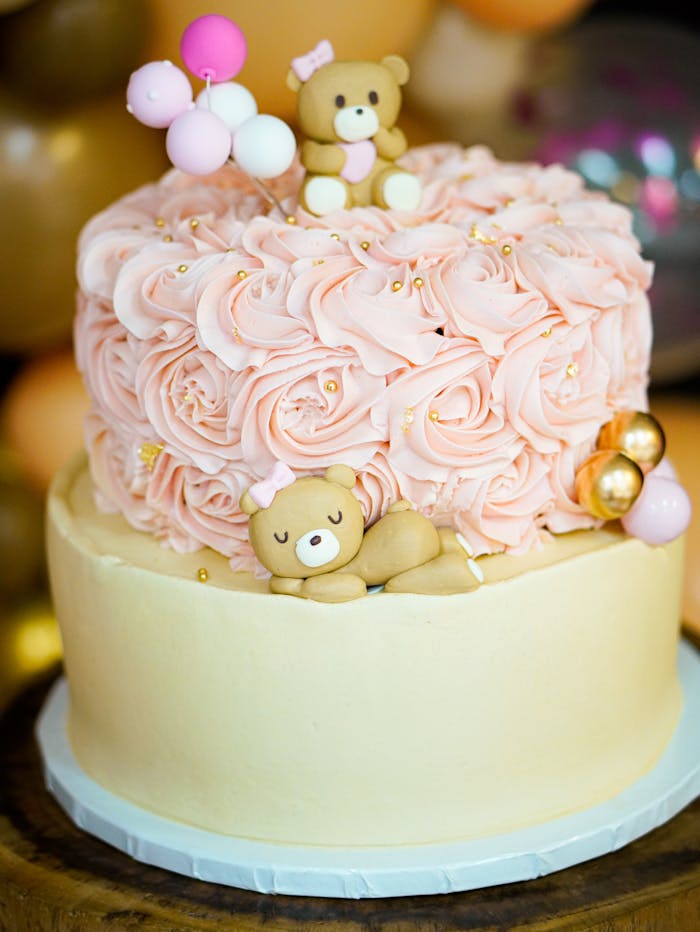 Adorable pink bear-themed cake with rose swirls for a baby shower.