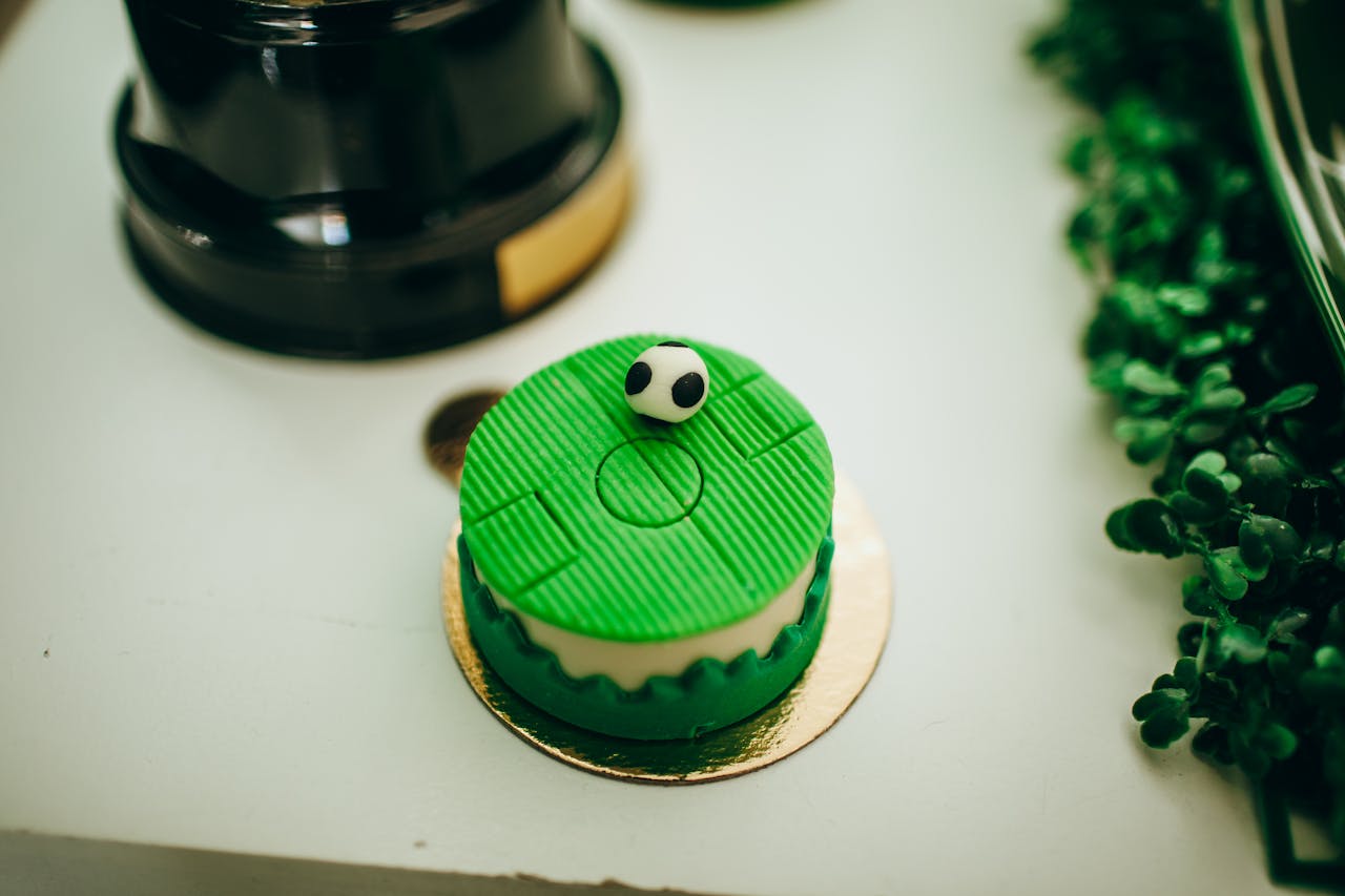 A small soccer themed cake with green icing and a fondant soccer ball top. Perfect for birthdays.